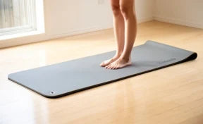 Yoga mat unrolled on a hardwood floor during a stretch